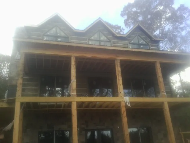 Dormers and porch framing on a large log home under construction — Roof Coating work by our crew in North Attleboro