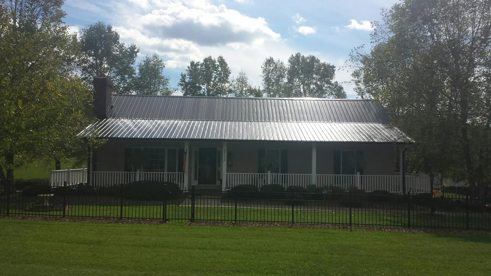 Gray metal roof on a brick ranch with a full width front porch — Gutter Guard Installation work by our crew in North Attleboro