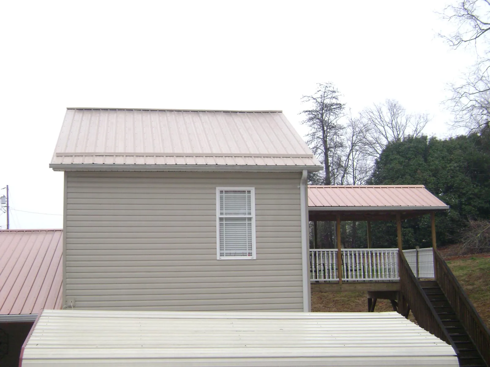 Tan metal roofs on a two story addition and attached porch, from a Roof Replacement job in North Attleboro