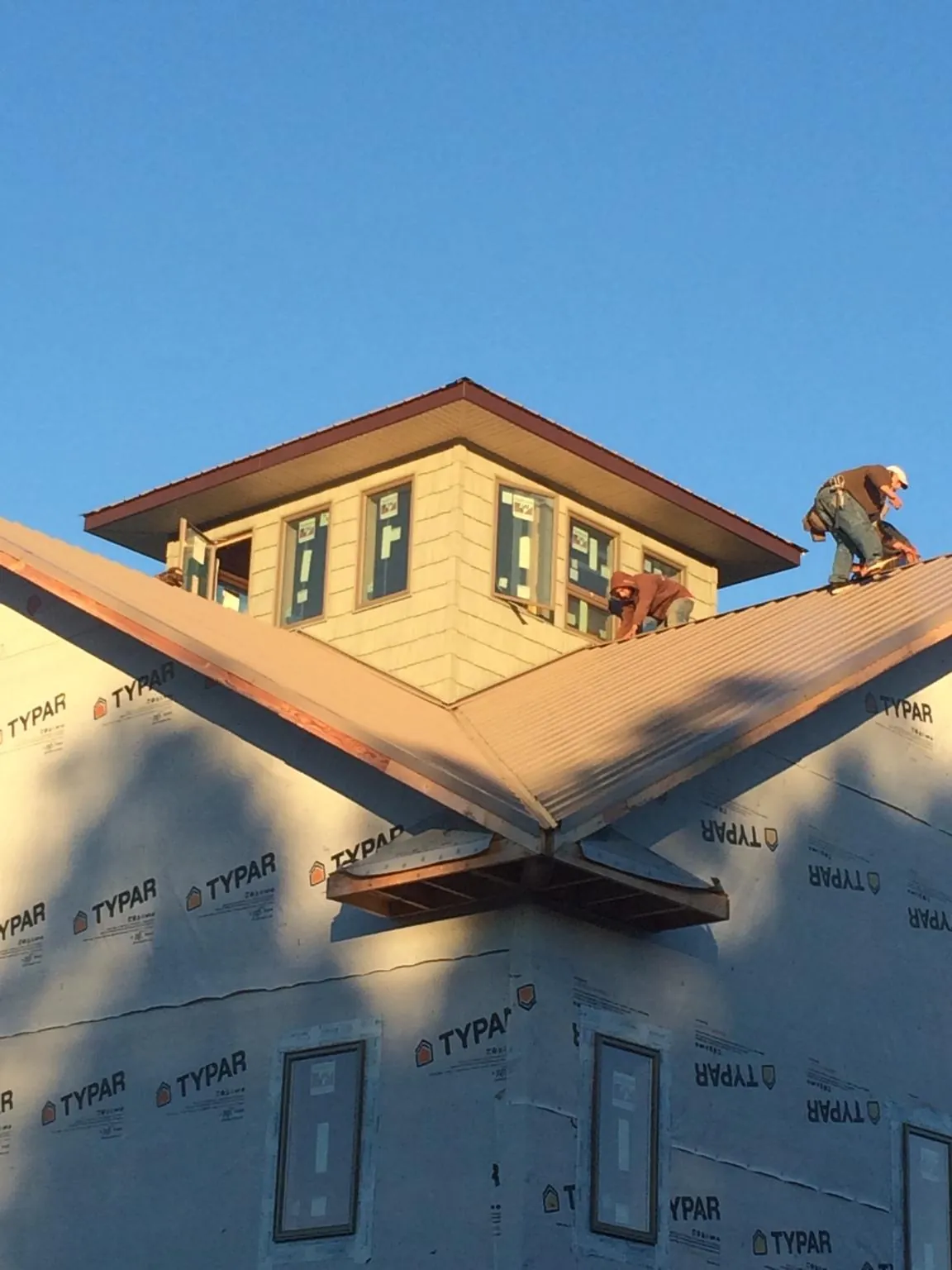 Roofers working around a rooftop cupola on a new metal roof at sunset — Roof Waterproofing in North Attleboro by Roofing Brothers